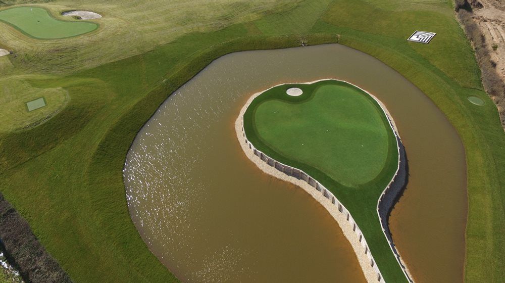 Kennewick Aerial view of a vibrant green synthetic grass island in a natural pond on a golf course